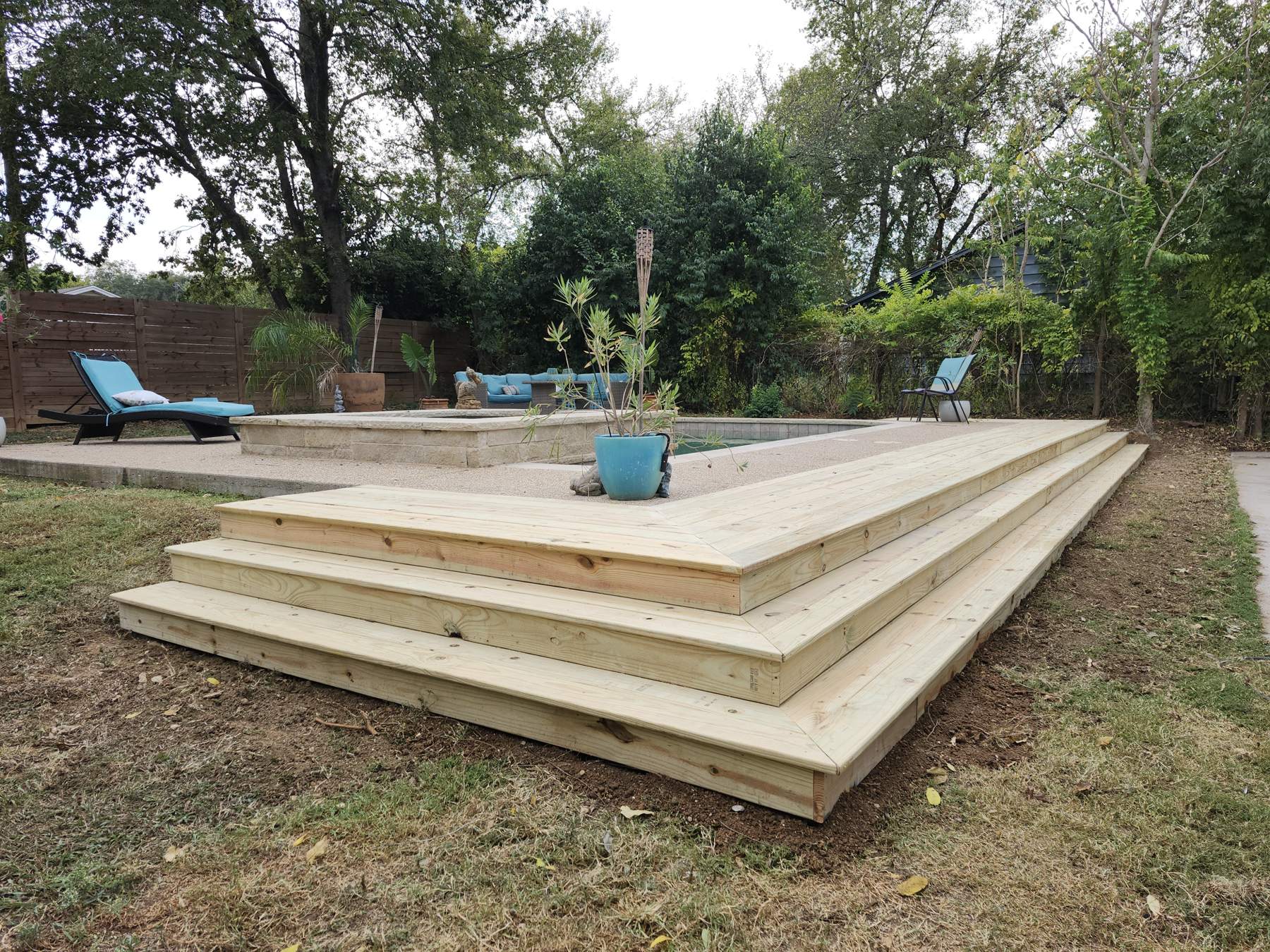 Wooden deck with wide steps around a backyard pool