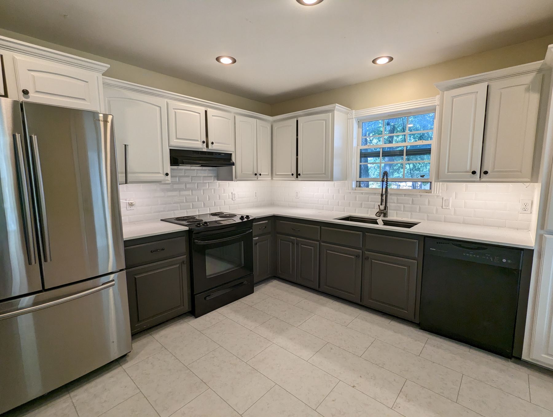 Kitchen with white upper cabinets, dark lower cabinets and a subway tile backsplash